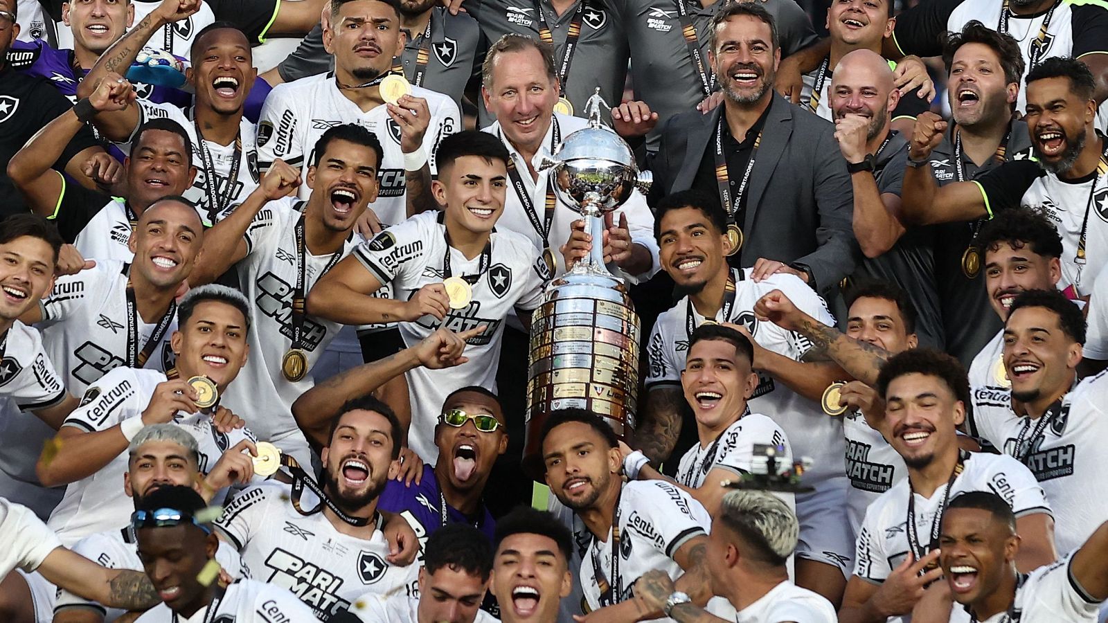 Jugadores del Botafogo celebran la victoria en la Copa Libertadores 2024, mostrando el trofeo y medallas de oro.