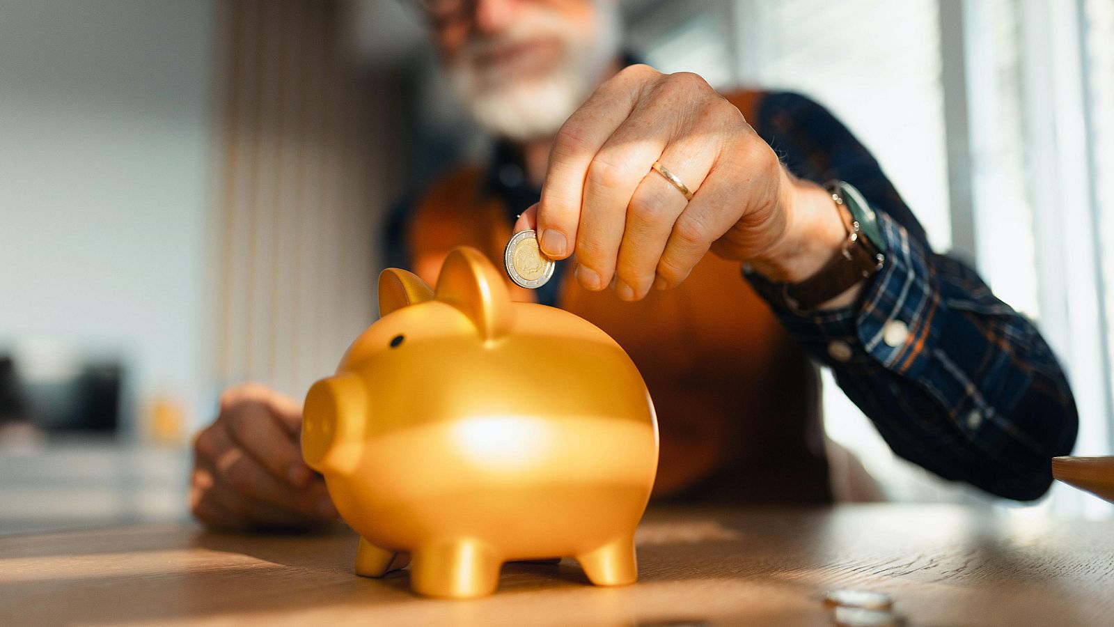 Un hombre metiendo dinero en una hucha