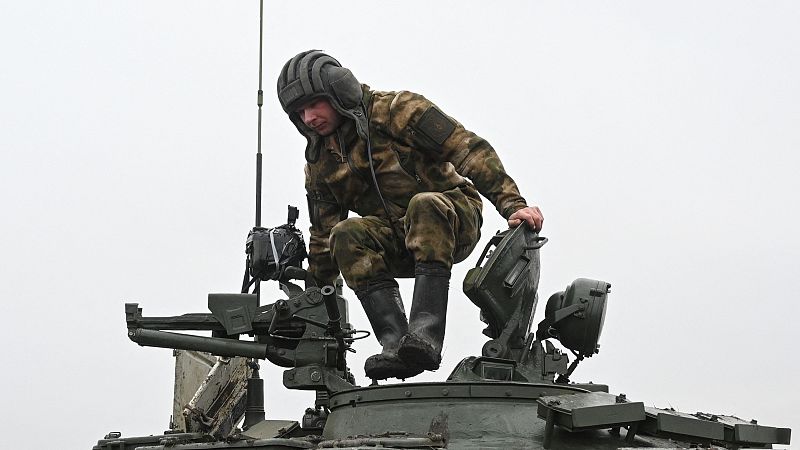 Soldado en uniforme de camuflaje sale de un tanque T-72; cielo gris; maniobras militares.
