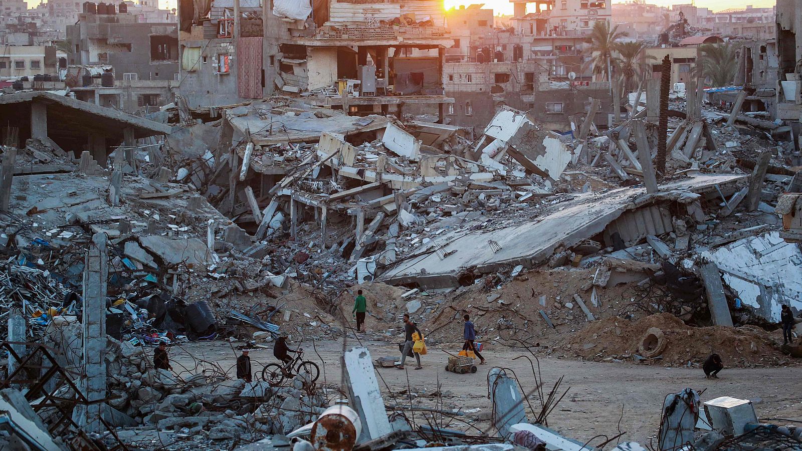 Palestinos caminan por un barrio devastado por los ataques israelíes en la ciudad de Jan Yunis