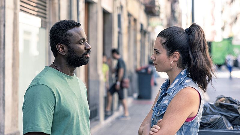 Tensión entre un hombre con camiseta verde y una mujer con prenda vaquera en una escena callejera. Imagen promocional del capítulo 5 de una serie de TVE.
