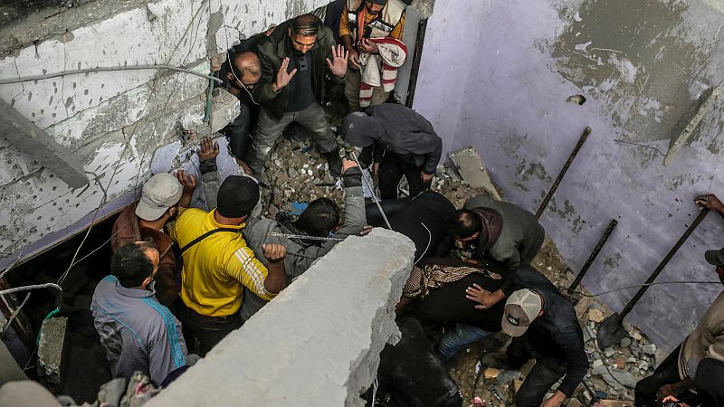 Personas colaboran en el rescate entre los escombros de un edificio derrumbado, mostrando preocupación en sus rostros.