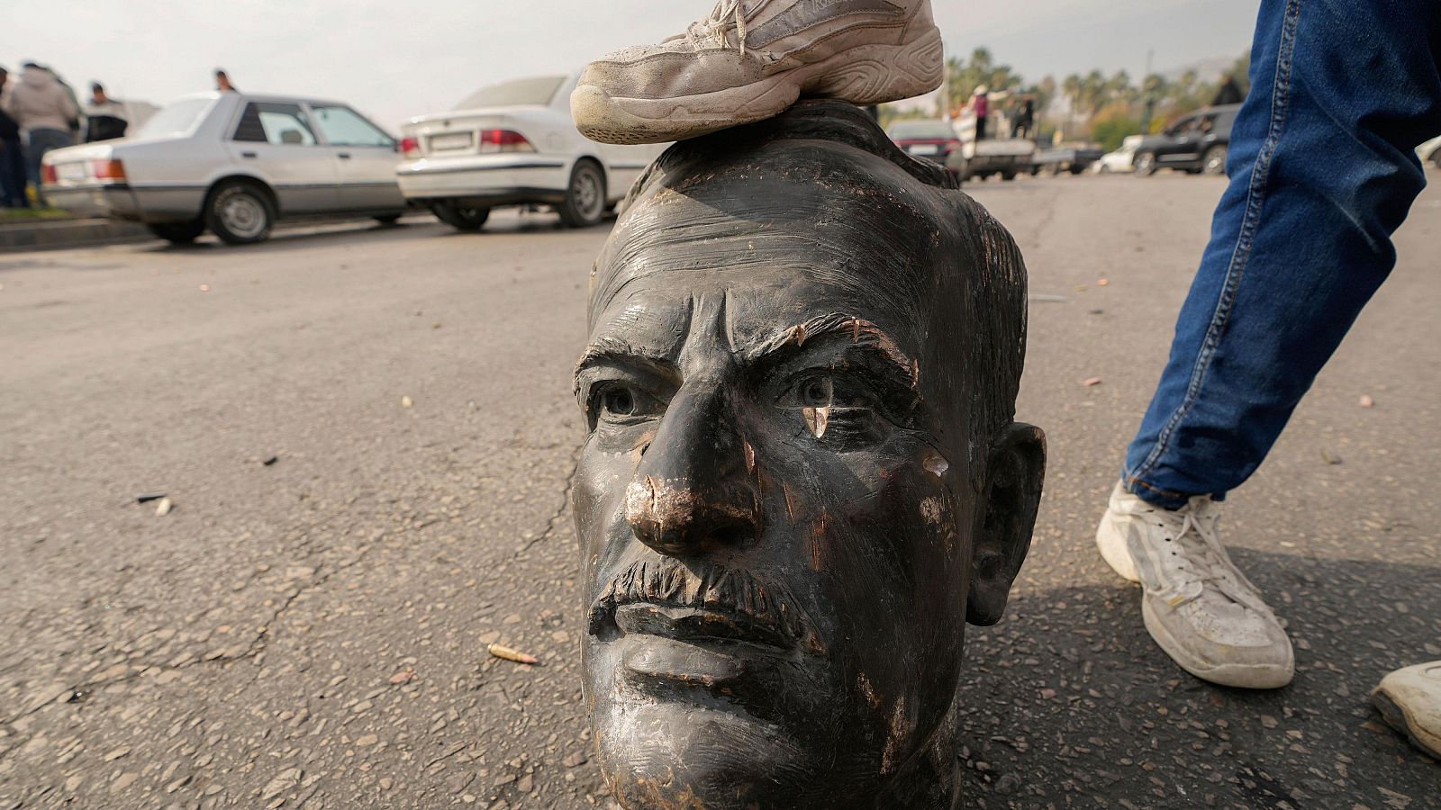 Un combatiente rebelde pisa un busto roto del difunto presidente sirio Hafez al Asad en Damasco