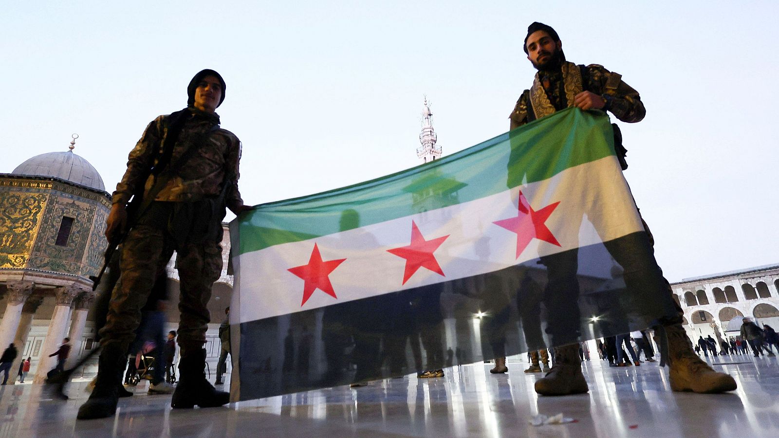 Dos combatientes rebeldes posan con una bandera de la oposición siria en la Mezquita Omeya