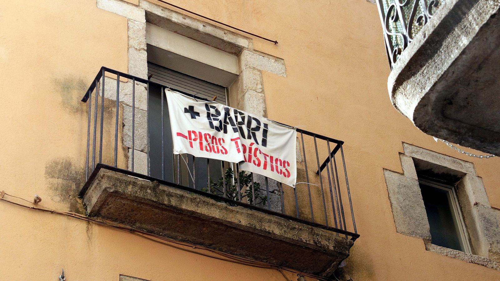 Pancarta '+ barri - pisos turístics' penjada en un balcó del Barri Vell de Girona | ACN