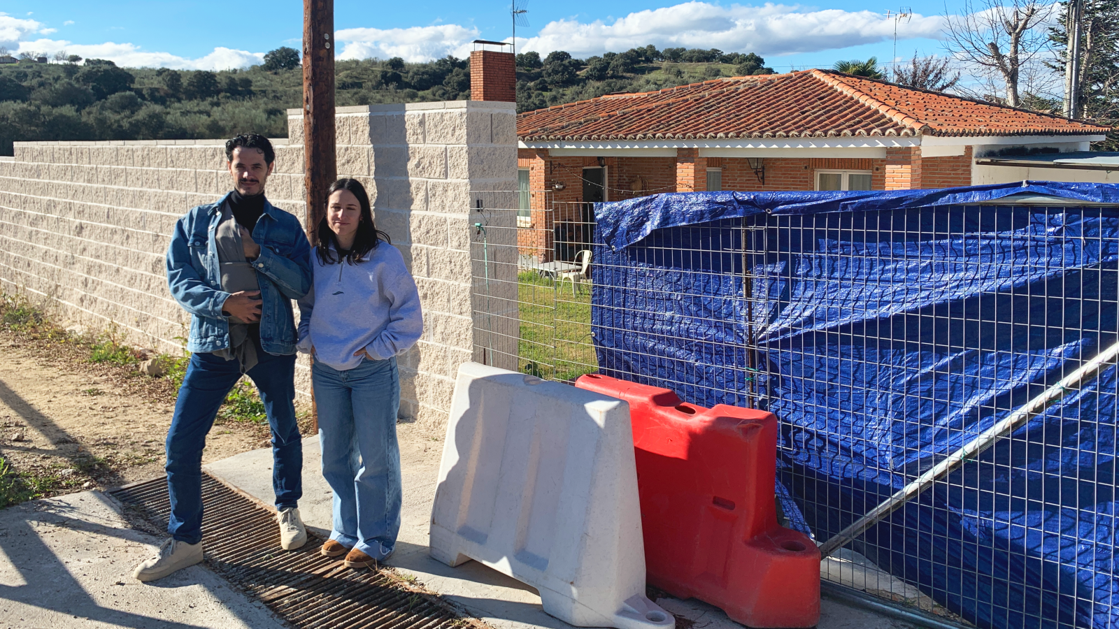 Roberto, Patricia, y su bebé Bran, junto a su casa en Villamanta, sin puerta por la DANA de 2023