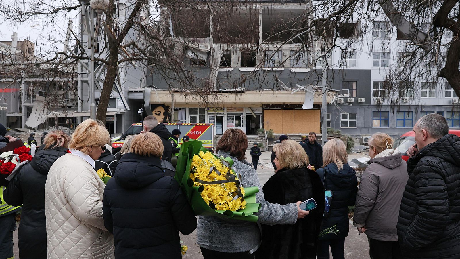 Varios ucranianos llevan flores cerca del lugar donde se produjo el impacto de un cohete contra una clínica privada en Zaporizhzhia, sureste de Ucrania