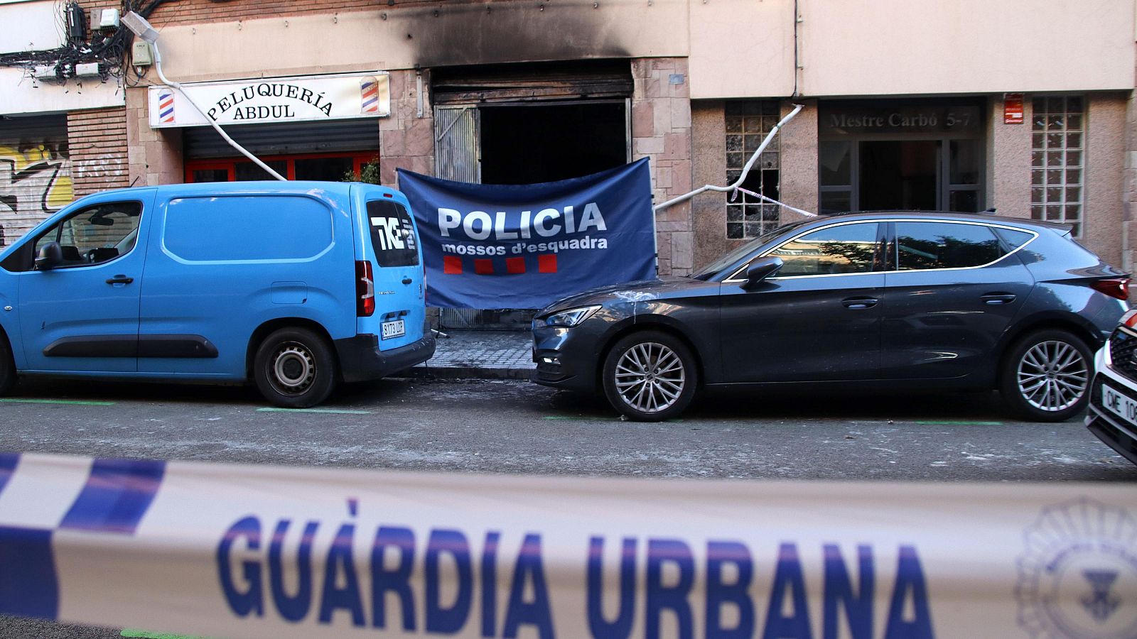 Una lona dels Mossos tapa l'entrada al baix incendiat al carrer Mestre Carbó de l'Hospitalet de Llobregat