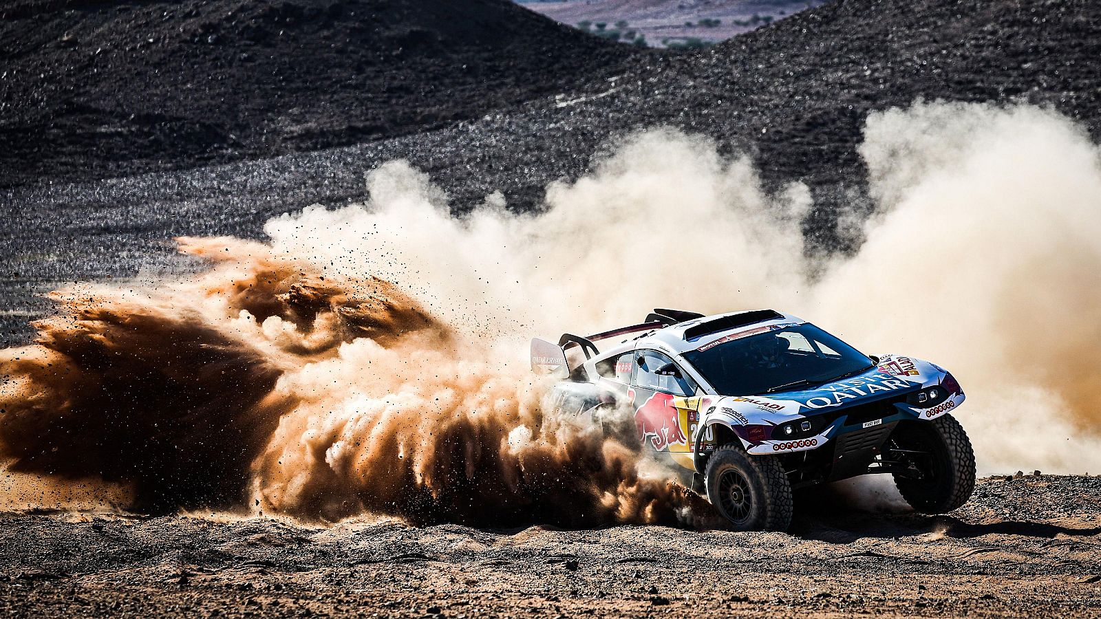 Potente vehículo de rally blanco y azul, con logo Red Bull, corre por un desierto levantando polvo.  Imagen evoca la intensidad del Dakar.