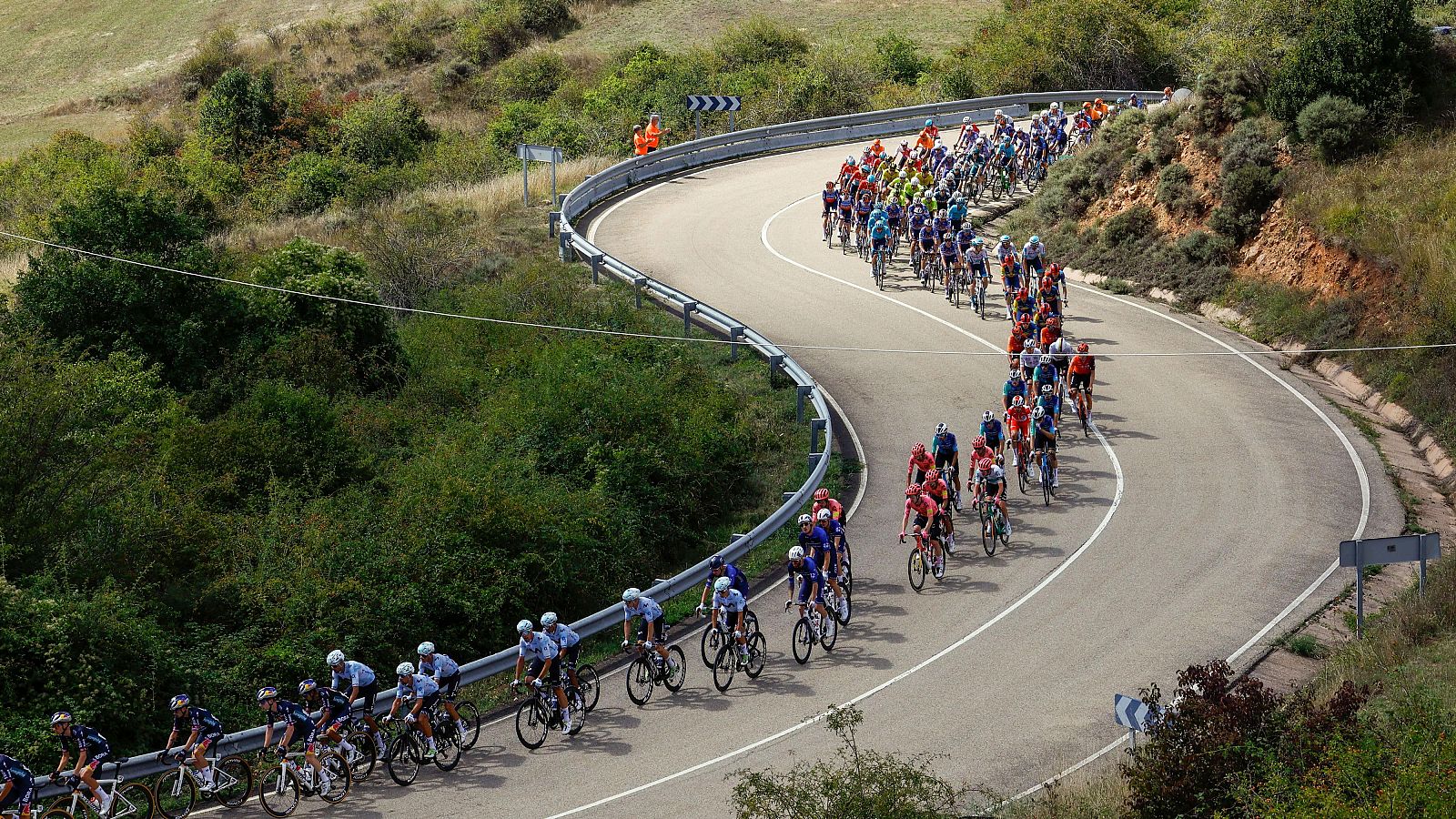 Ciclistas en el pelotón por un tramo de carretera con curvas en una etapa de la última Vuelta ciclista a España