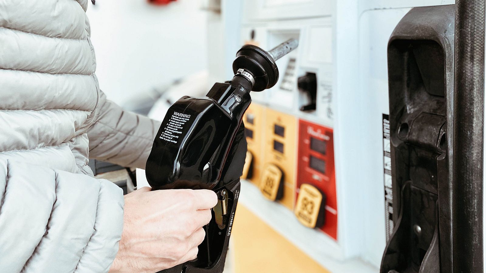 El precio de los carburantes sigue al alza a las puertas de Navidad: Una persona con abrigo reposta en una gasolinera