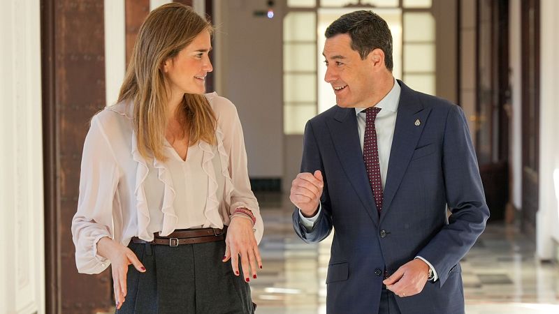 El presidente del Gobierno español conversa con una mujer en un espacio institucional. Ambos visten de forma formal y parecen mantener una conversación seria.