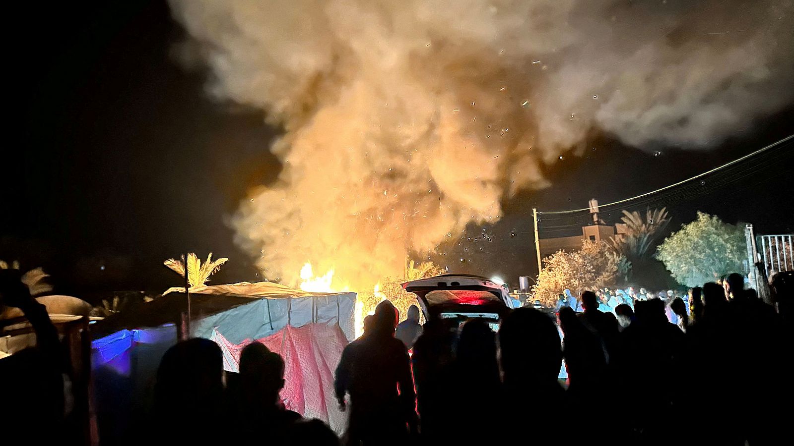 La población desplazada en la zona humanitaria observa el fuego en las tiendas de campaña