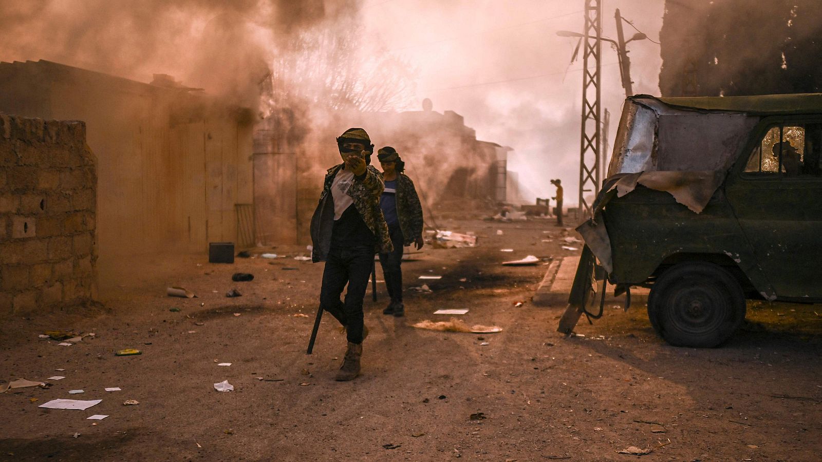 Dos personas caminando entre columnas de humo en Damasco, Siria