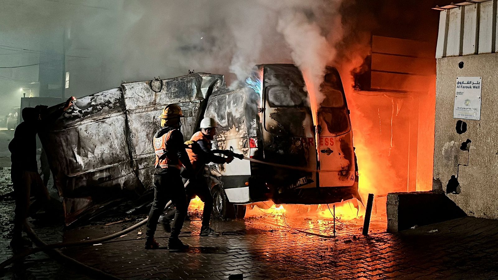 Varias personas apagando un incendio en una furgoneta de la televisión Al Quds en Gaza