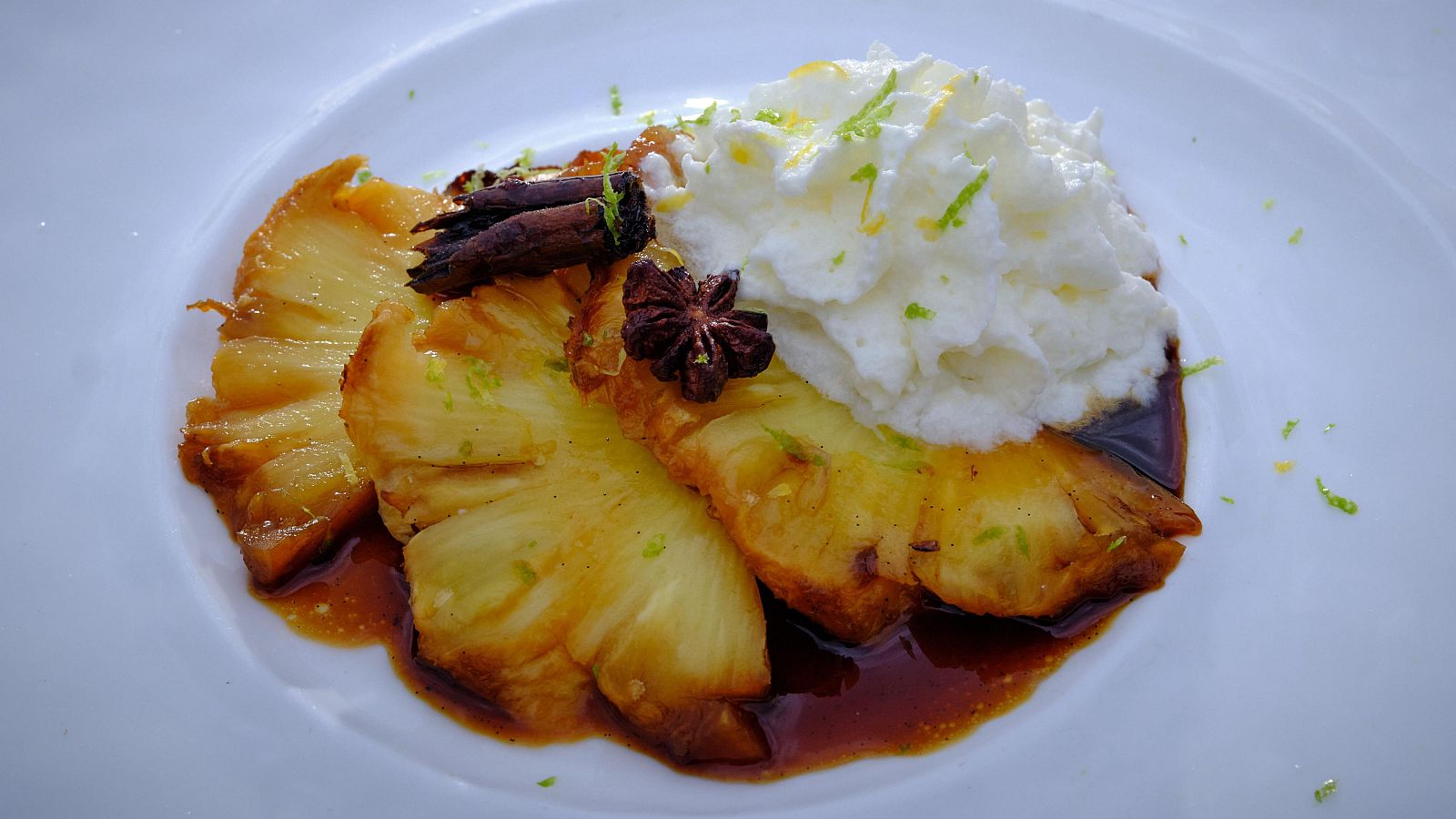 Piña asada con espuma de yogur y coco, especias y sirope.  Ralladura de lima y textura caramelizada en la piña.