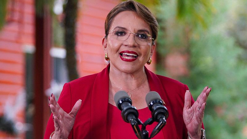 Xiomara Castro, presidenta de Honduras, ofrece un mensaje a la nación; habla con expresión seria, gesticulando con las manos levantadas frente a dos micrófonos.