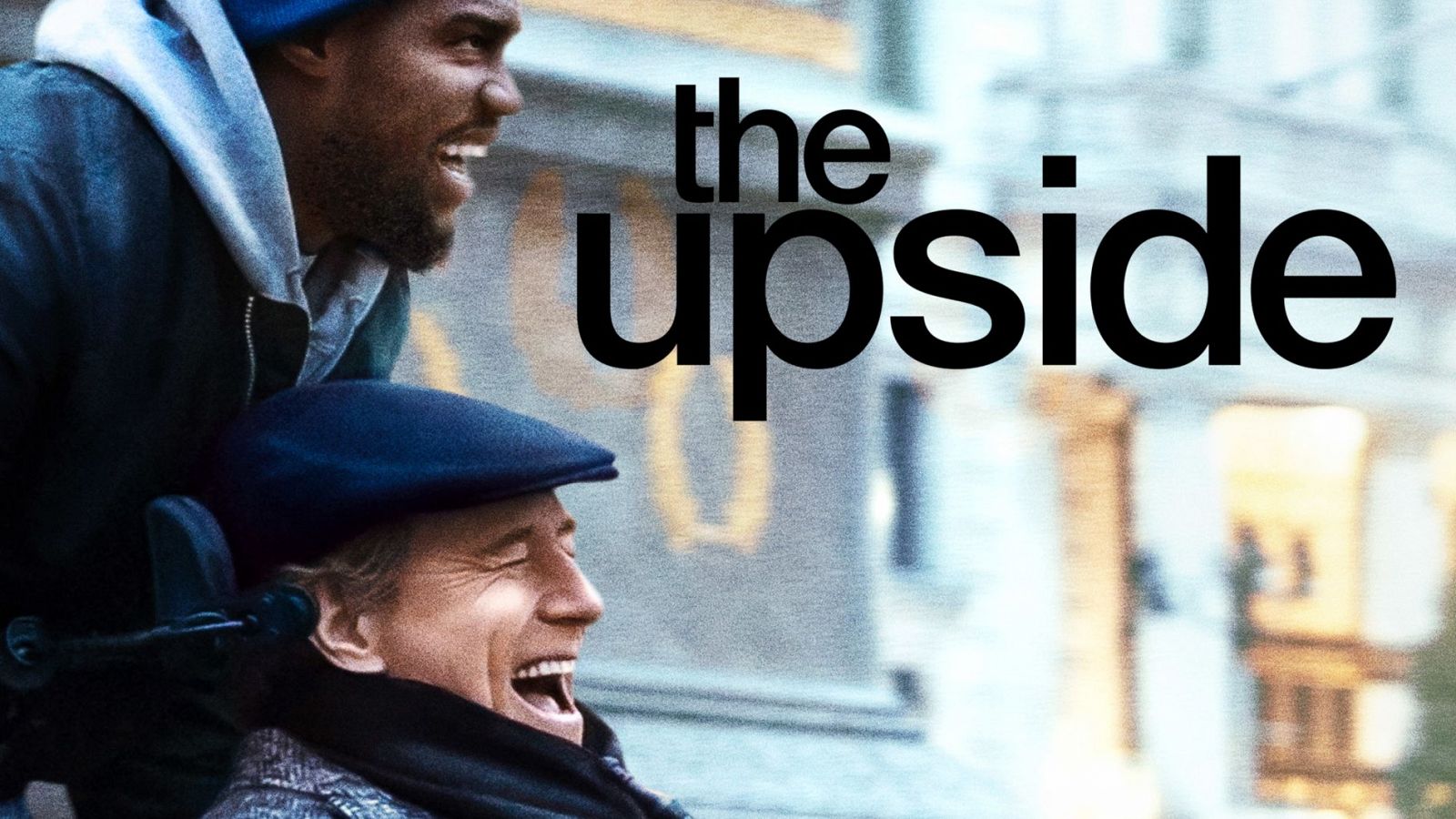 Dos hombres, uno en silla de ruedas, ríen en un cartel de película con fondo urbano desenfocado. El título "The Upside" destaca en letras grandes.