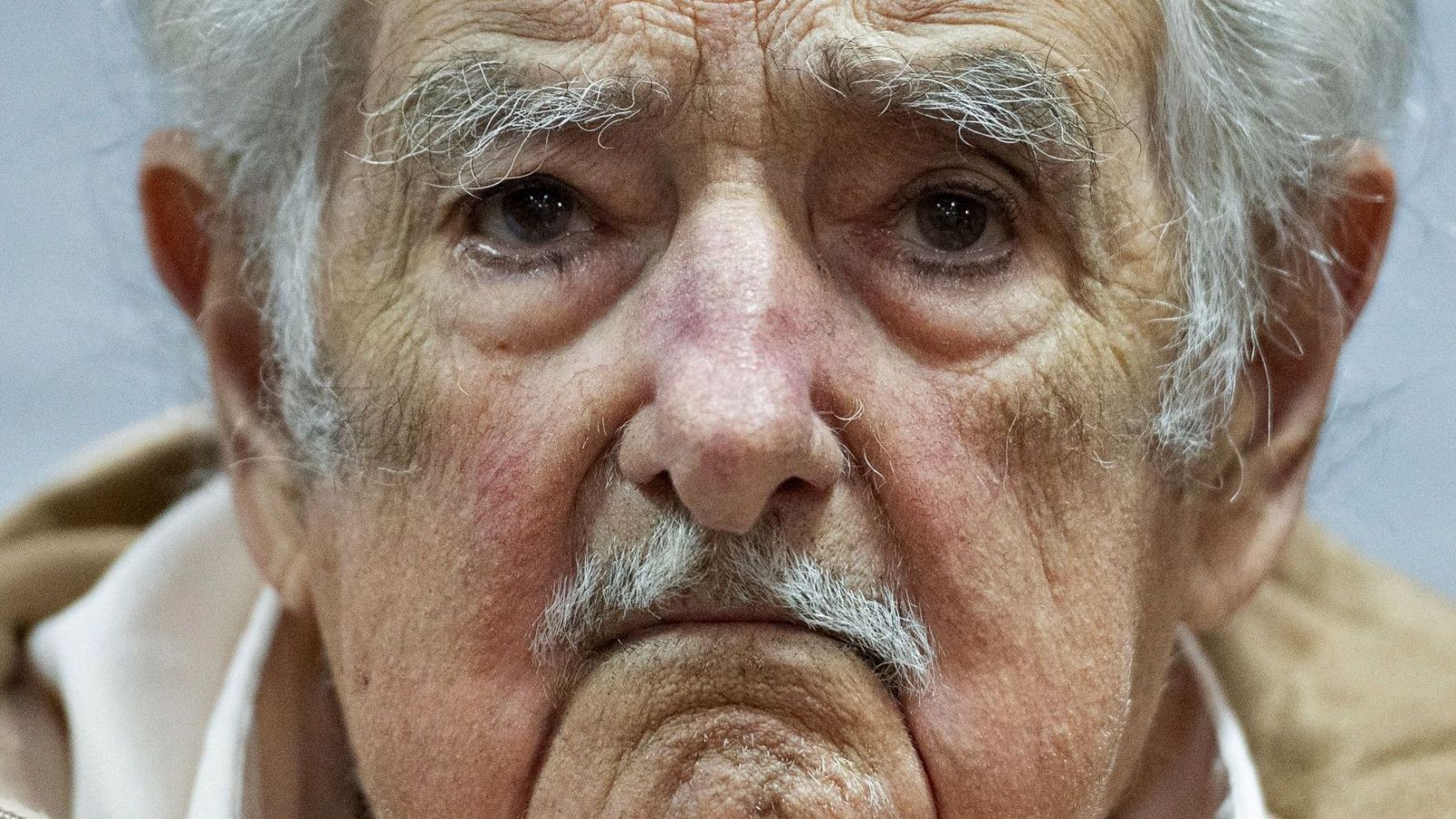 Imagen de un hombre mayor con expresión seria y rasgos faciales que denotan la edad.  Su mirada transmite tristeza o resignación.