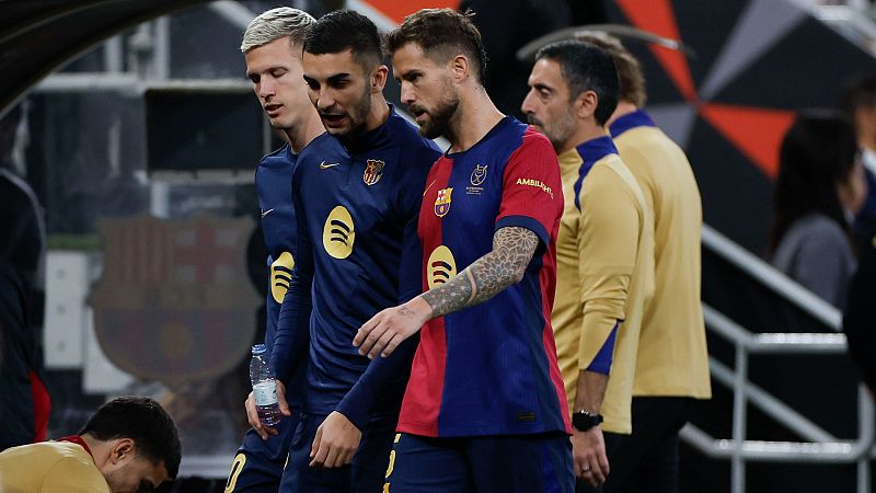 Iñigo Martínez, con la camiseta del Barça, conversa con compañeros de equipo durante una pausa en el juego o entrenamiento. Se observa un miembro del cuerpo técnico cercano.