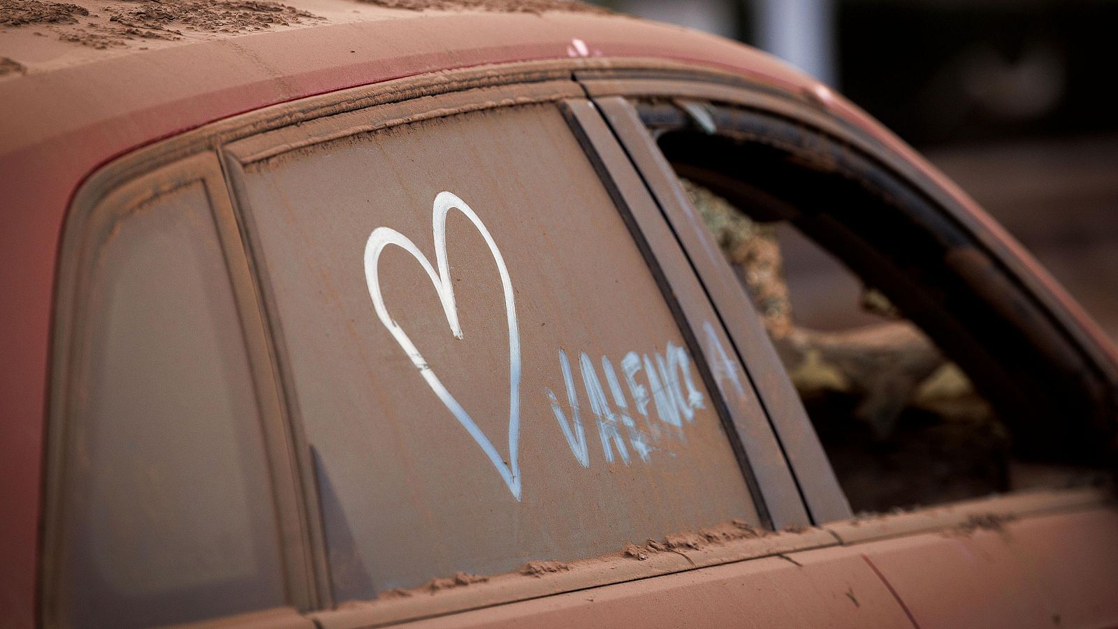 Un corazón pintado en un coche cubierto de polvo en Paiporta, zona cero de la dana de 2024