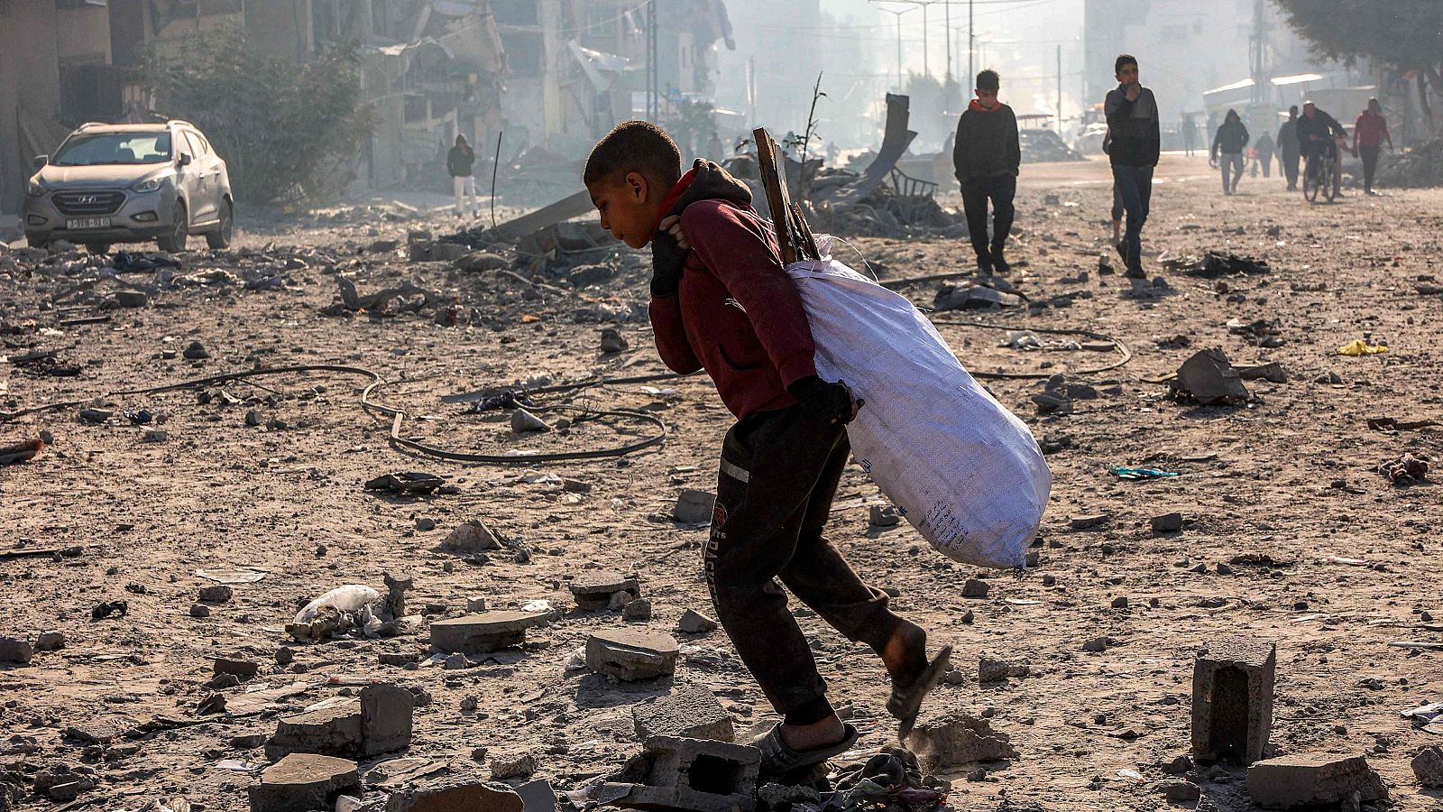 Tregua en Gaza: Un niño camina con un saco en medio de los escombros de un bloque residencial en la ciudad de Gaza