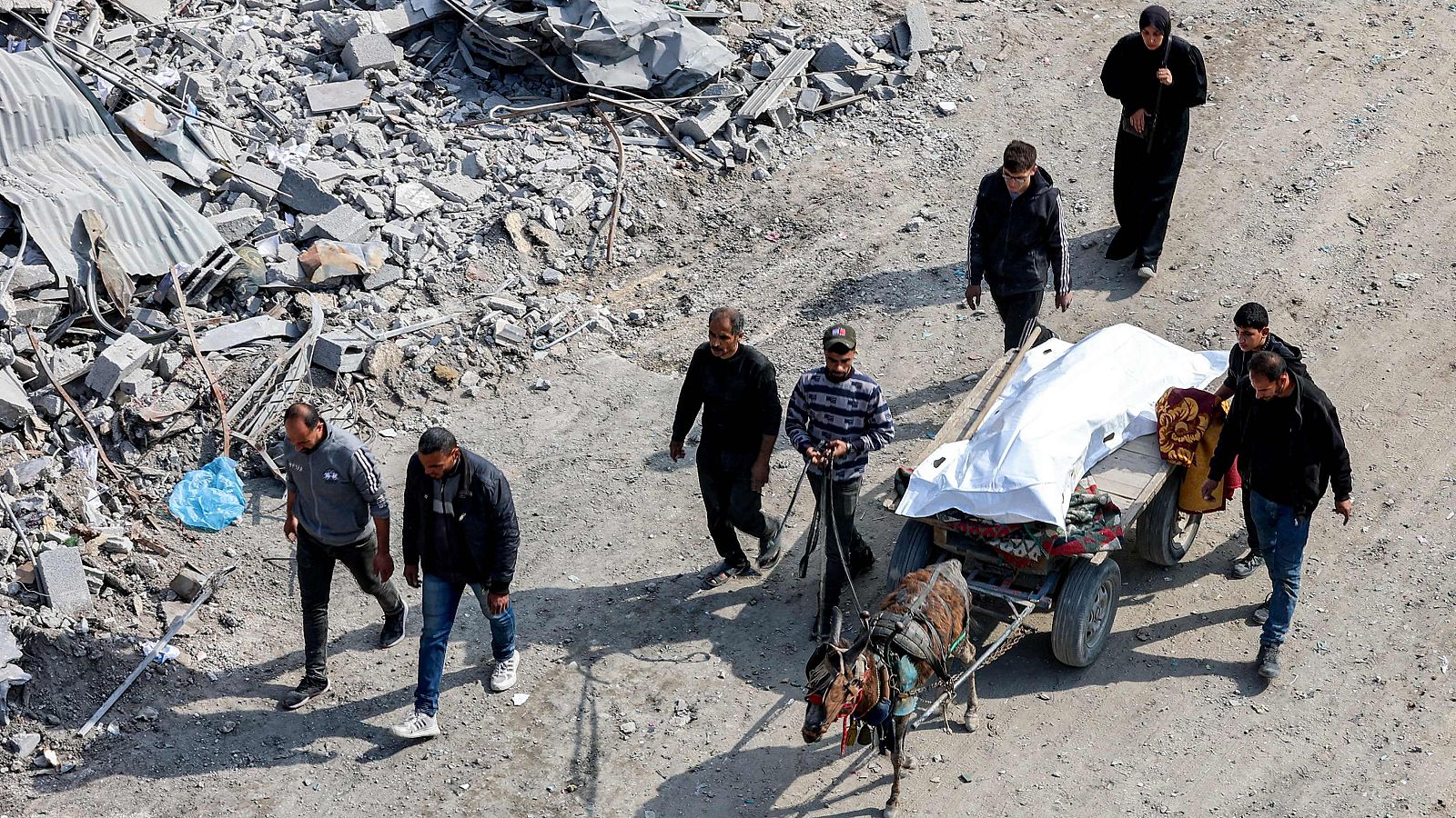 El cadáver de un palestino asesinado en la ofensiva israelí es transportado con un carro entre los escombros