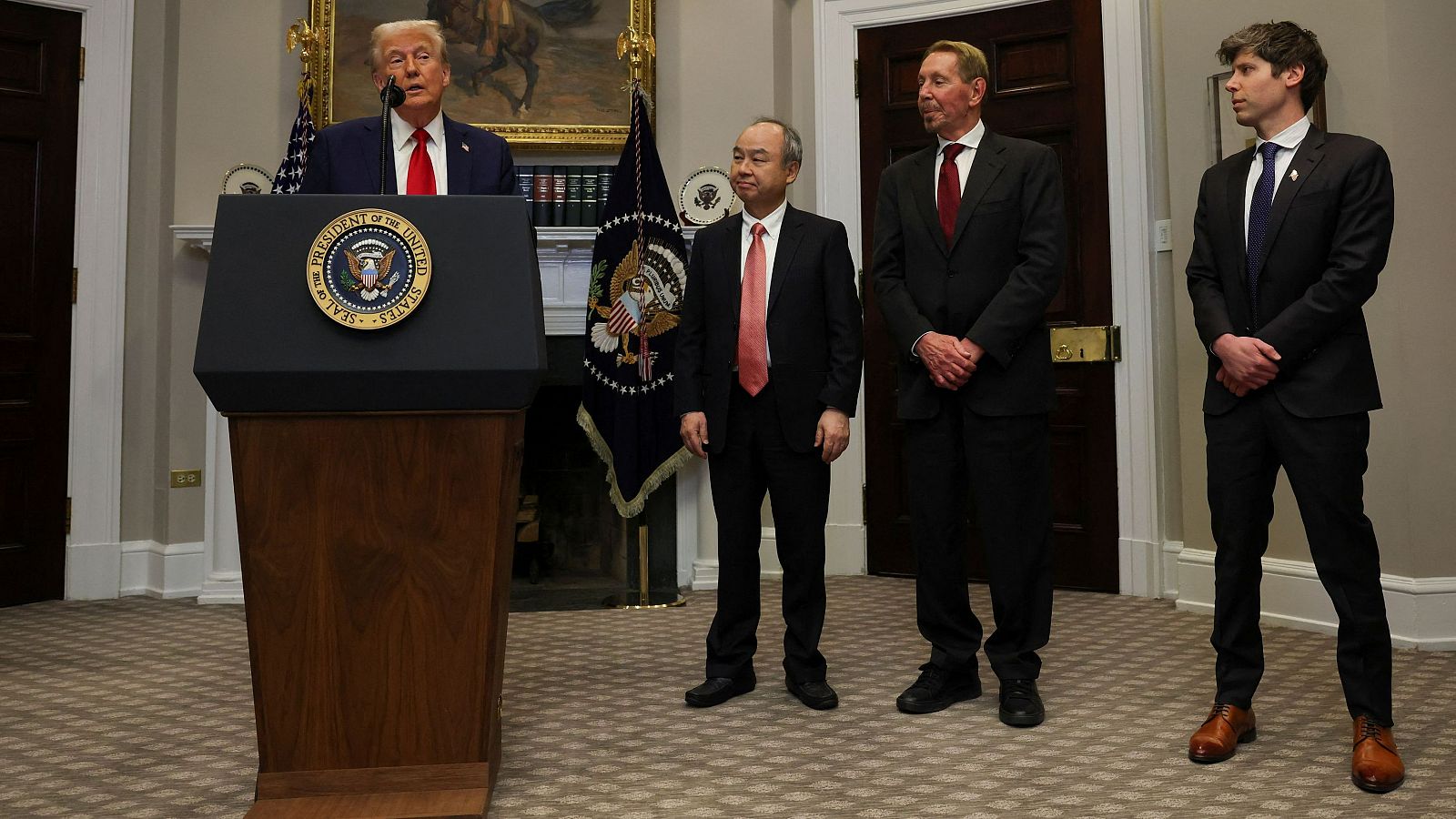 Comparecencia de Donald Trump en la Casa Blanca. Viste traje azul marino y corbata roja; le acompañan tres hombres en traje con corbatas rosa, azul marino y morada.