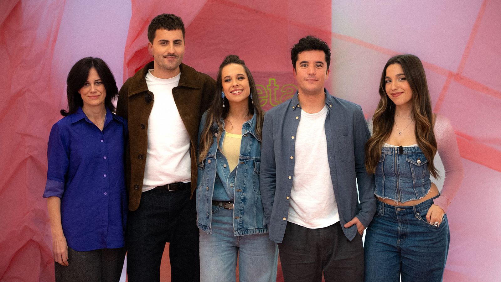 Cinco personas, incluyendo a Delia Rodríguez, posan juntas para una foto con un fondo rosa. Se aprecian diferentes estilos de ropa.