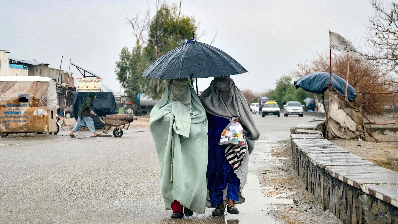 Mujeres afganas caminan por una calle con paraguas bajo la llovizna en Kandahar