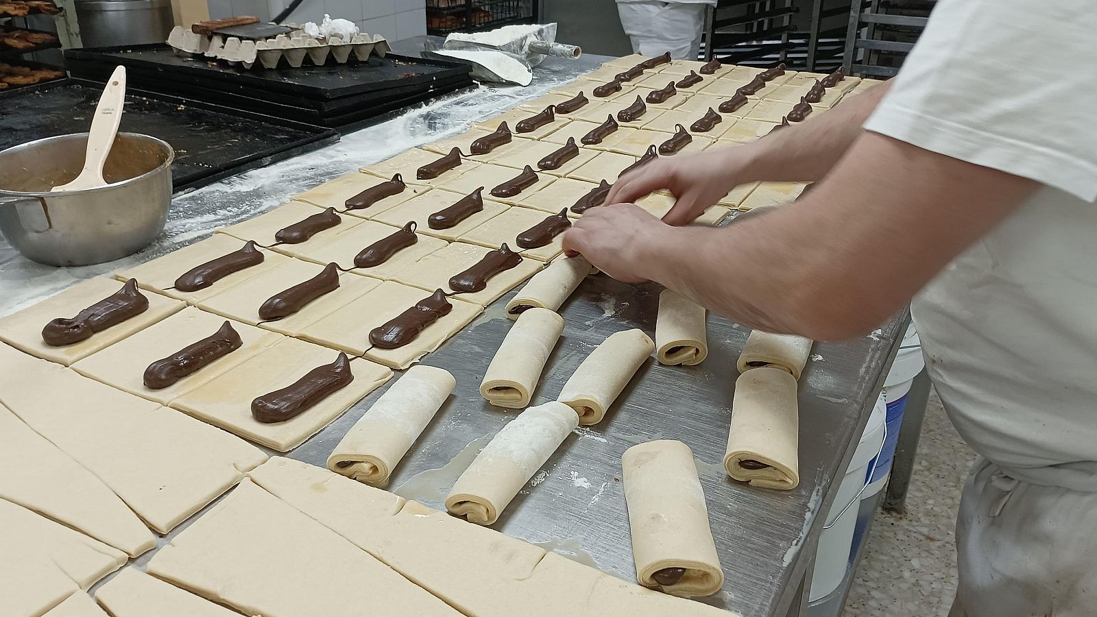 Las manos de Augusto Israel Aladrén, repostero en Horno Ismael, rellenando napolitanas de chocolate