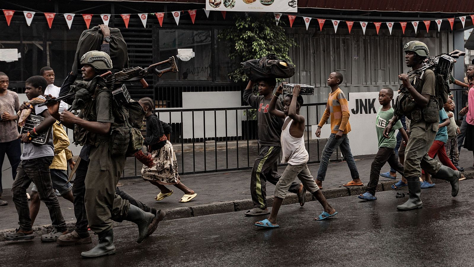 Miembros del grupo armado M23 caminan junto a los residentes por una calle del barrio de Keshero en Goma.