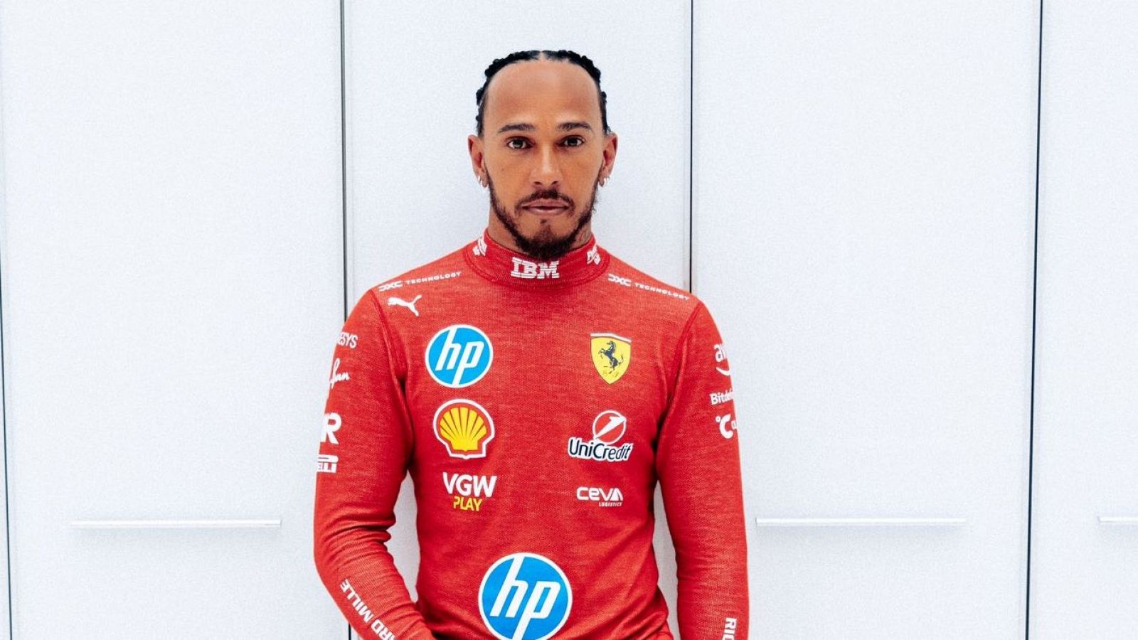 Imagen de Lewis Hamilton con un mono de carreras rojo de Ferrari, mostrando logos de patrocinadores como IBM, HP, Shell y Puma.