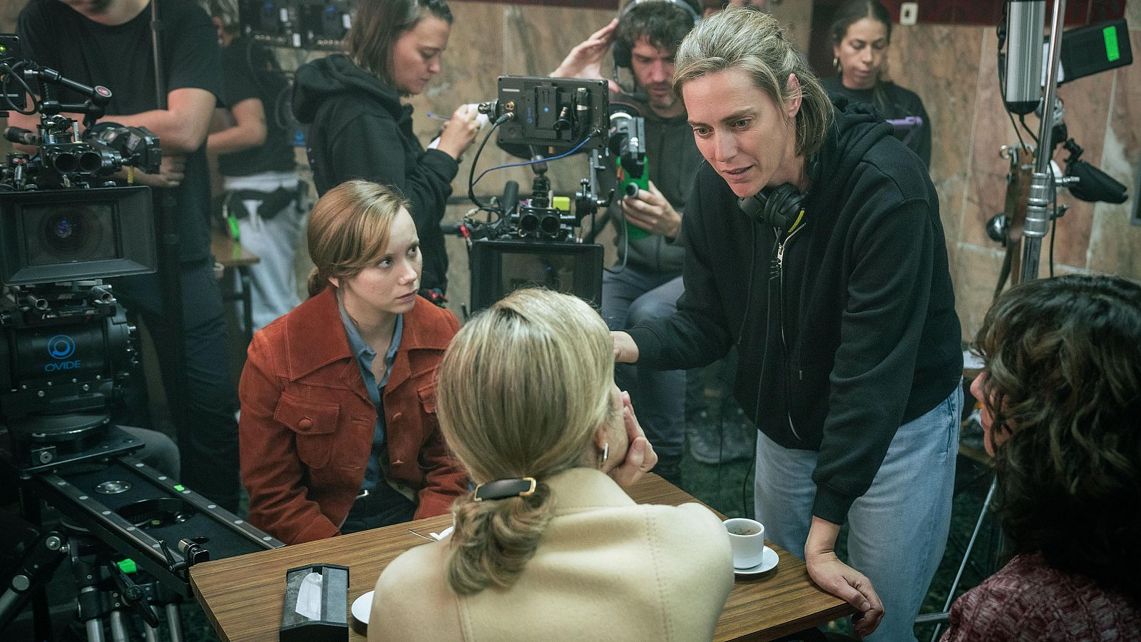 Rodaje de escena interior: tres actrices en una mesa, una directora con auriculares les da indicaciones.  Cámaras y micrófonos presentes.