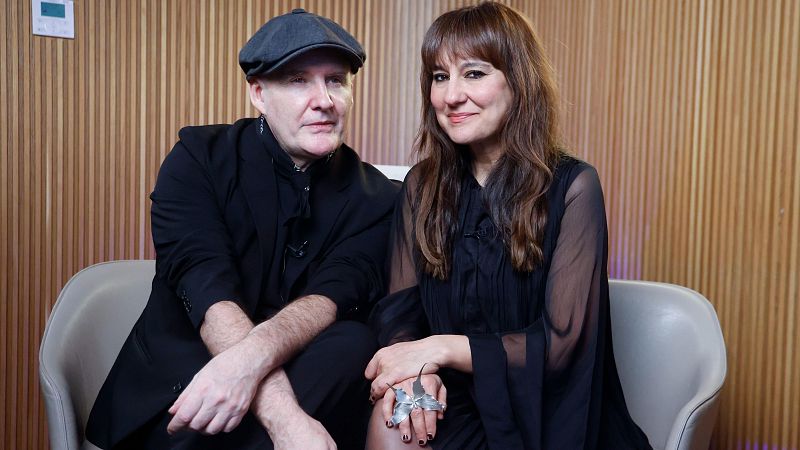 Eva Amaral y Juan Aguirre, del grupo musical Amaral, durante una entrevista. Ella viste blusa negra y anillo; él, boina y chaqueta negra. Fondo de madera clara.