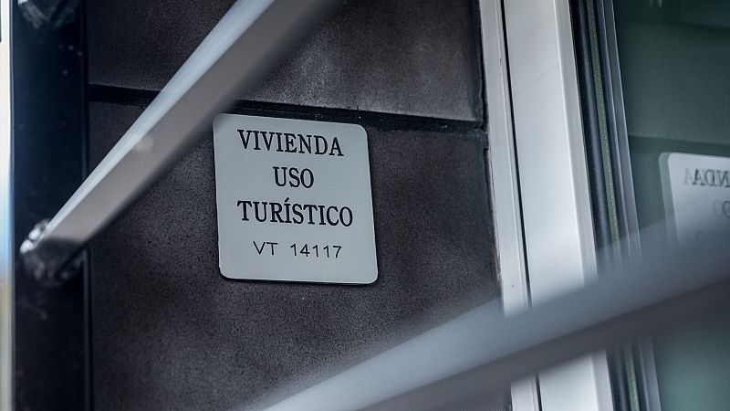 Placa 'VIVIENDA USO TURÍSTICO VT 14117' en fachada de edificio junto a ventana. Elementos metálicos visibles.