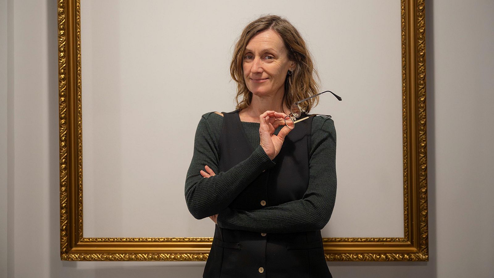 Rosa Galido amb les ulleres a la mà davant d'un marc d'un quadre buit