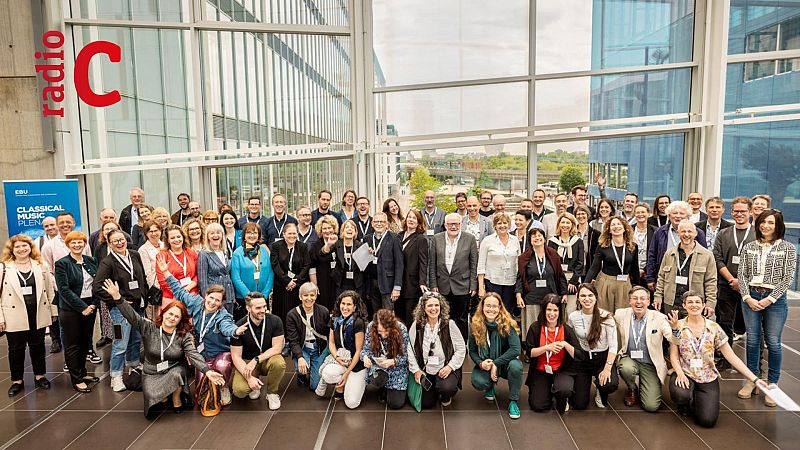 Grupo numeroso de personas en un evento de música clásica de la UER.  Se ven logos de la UER y una emisora de radio.  Imagen tomada en un edificio moderno.