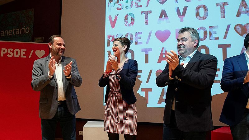 Acto político con José Luis Ábalos, María Chivite y Santos Cerdán aplaudiendo ante una pantalla con el logo del PSOE y el mensaje "VOTA PSOE".