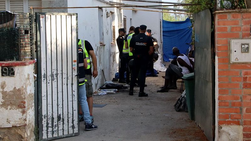 Operativo policial en una propiedad (número 92 visible).  Una persona está detenida o interrogada en el interior, con objetos esparcidos en el suelo.