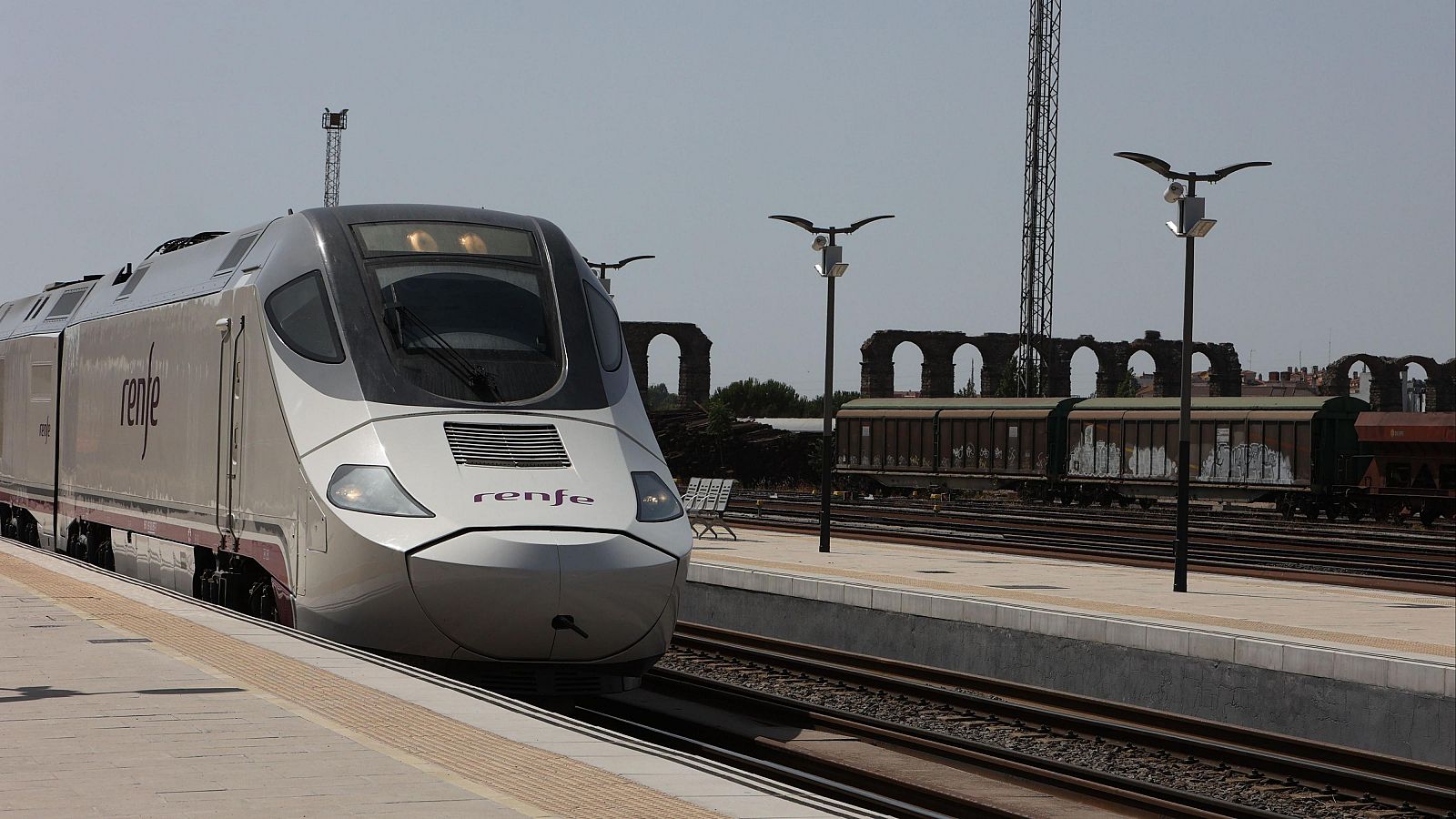 Tren de alta velocidad Renfe detenido en estación.  Vagones de mercancías y acueducto visibles.  Incendio causa interrupción del servicio.