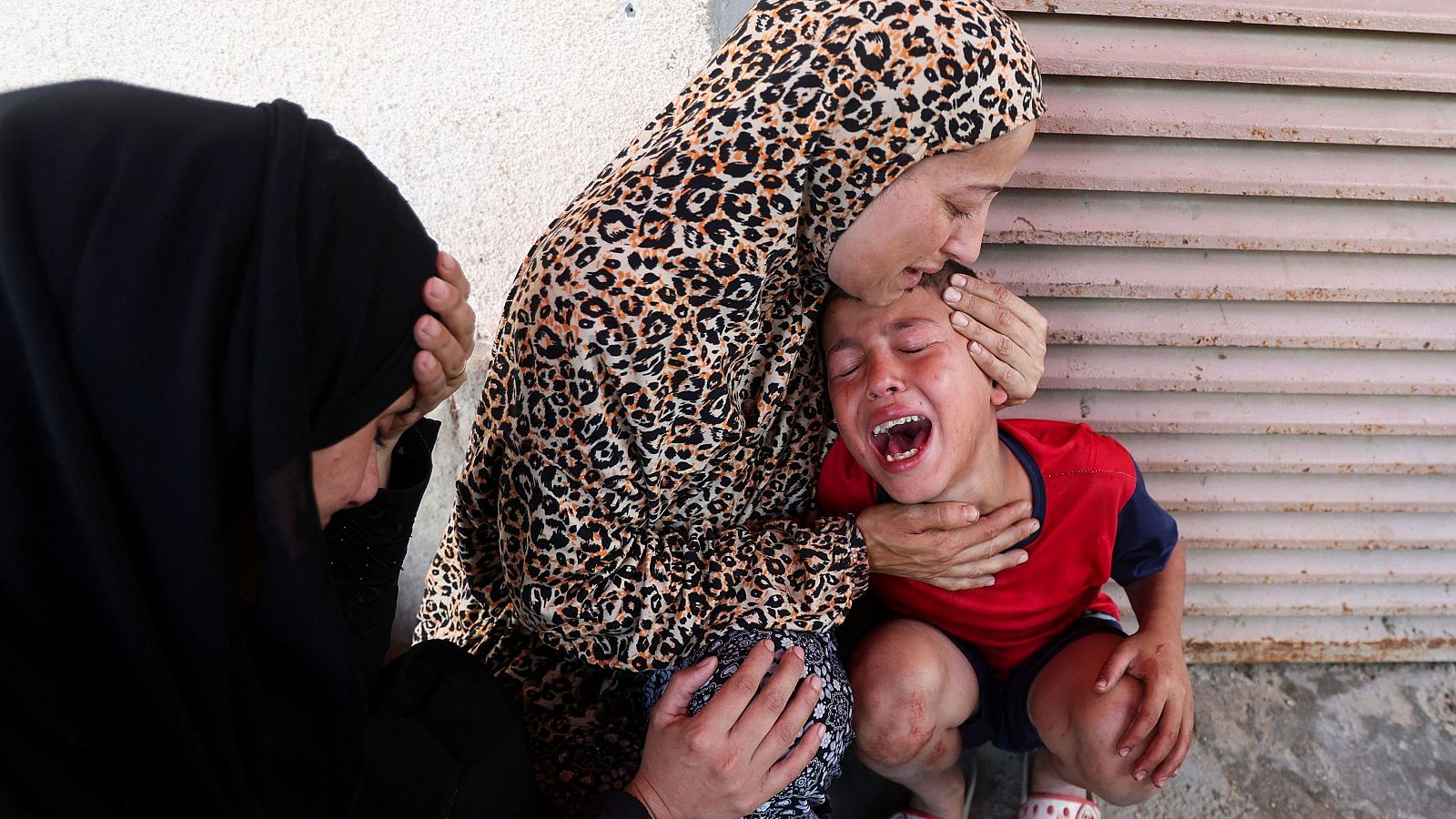 Una mujer palestina consuela a un niño tras el ataque israelí en Deir al-Balah