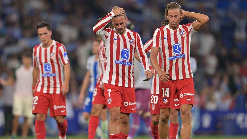 Jugadores de fútbol, con camisetas rojas y blancas a rayas, muestran gestos de abatimiento tras un partido.  Uno de ellos, con el dorsal 14, se lleva la mano a la cabeza.