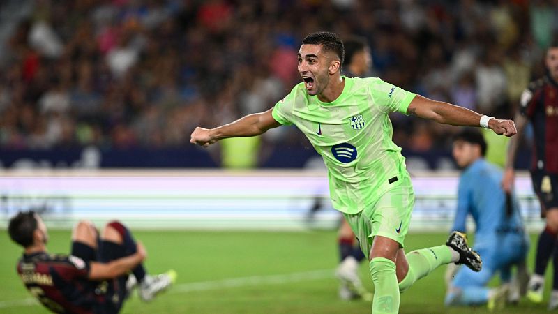 Jugador de fútbol celebrando un gol; viste camiseta verde fluorescente con logo en el pecho; expresión de alegría.