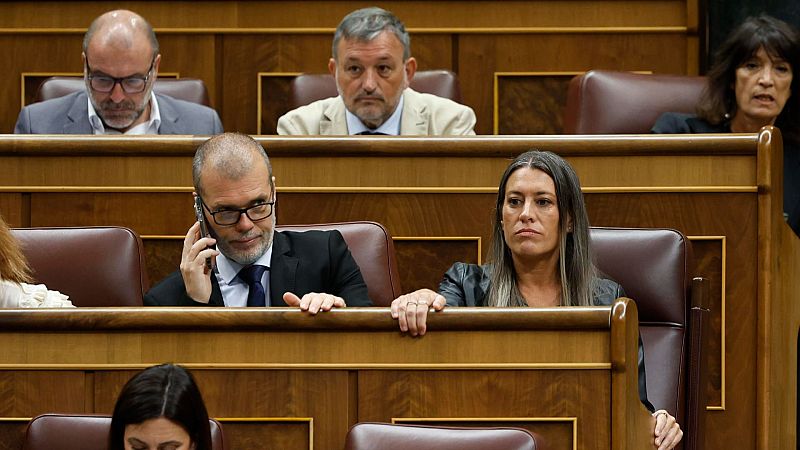 Dos portavoces de Junts en el Congreso de los Diputados; uno sentado y otro hablando por teléfono.