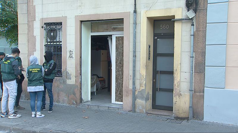 En la calle, frente a un edificio, se observa un grupo de agentes uniformados. Uno de ellos porta una prenda que lo identifica. En la puerta del edificio se distingue el número 560.
