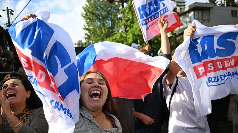 En una celebración política, un grupo de personas festeja con banderas y pancartas, mostrando alegría y entusiasmo. Se observa el nombre de un candidato presidencial y un lema esperanzador.
