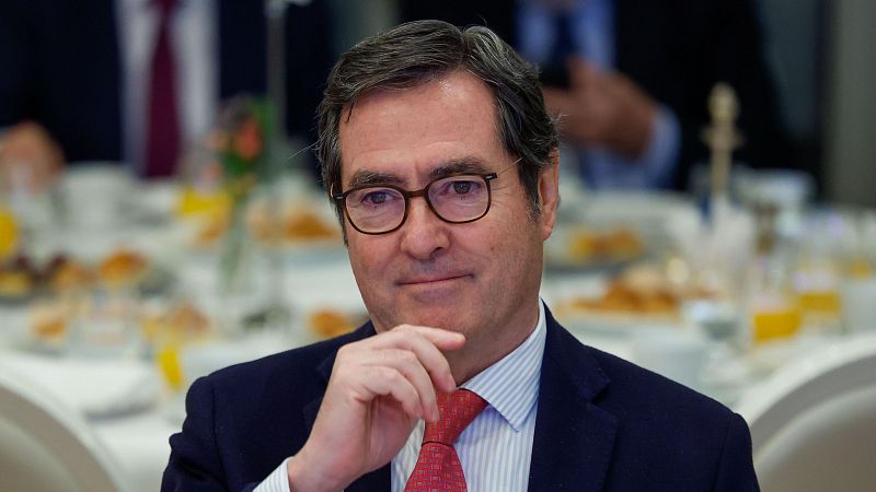 José Luis Escrivá Belmonte, con gafas y corbata roja, posa pensativo. Se encuentra en un entorno con una mesa y comida, posiblemente en un evento o reunión.