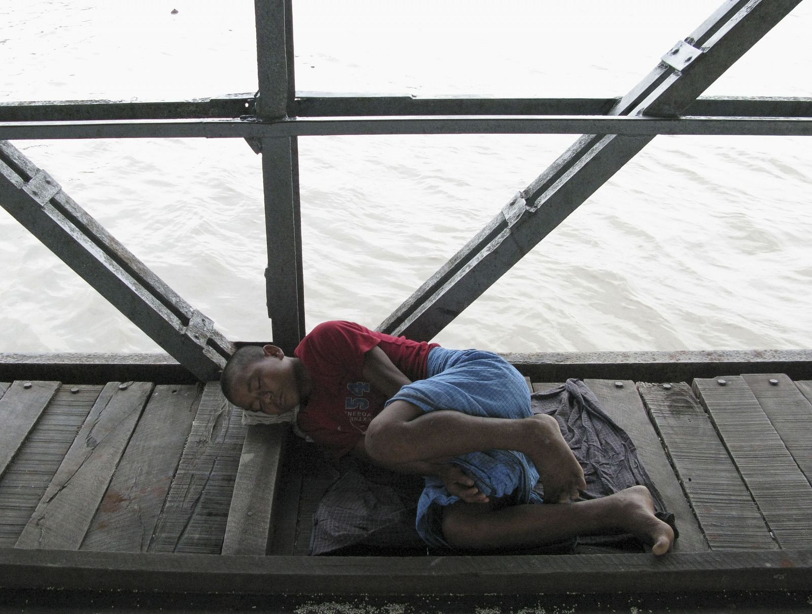 Un niño duerme en un puerto sobre un río crecido en Rangún, Birmania.