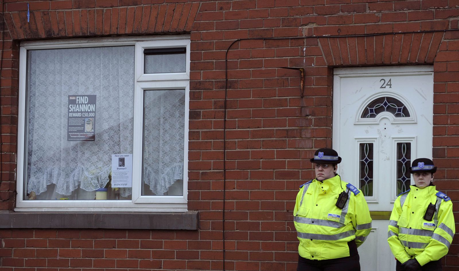 Police officers stand outside the house of Shannon Matthews in Dewsbury, Northern England